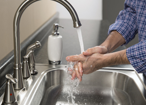 Closeup of hands in sink with running water.