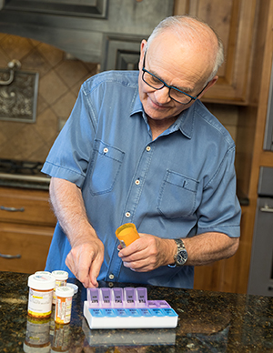 Man filling pill organizer with medications.