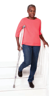 Woman walking down stairs with crutch.